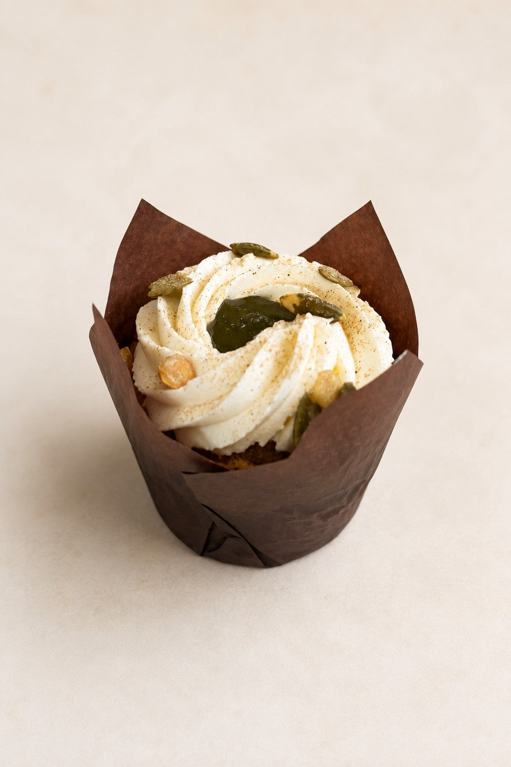Muffin Carotte à la cardamome de Batida - muffin dans une caissette brune, avec crème et graines de courge