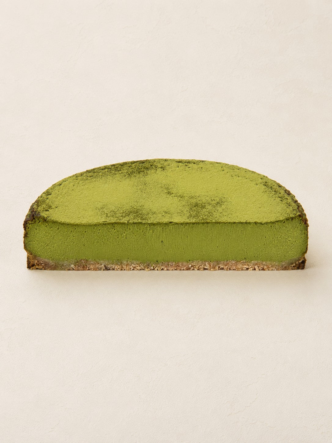 Matcha - White Chocolate Cheesecake by Batida - half a cheesecake from the side, cross-section with the oat base