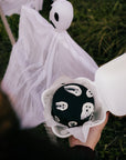 Tort bento z duchami trzymany obok halloweenowej dekoracji