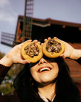 Dwa dyniowe crumble cookies z pestkami dyni trzymane przy oczach