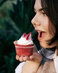 Dziewczyna gryzie muffina red velvet z halloweenową dekoracją