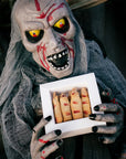 Halloweenowa maska trzyma pudełko ciastek paluchy wiedźmy