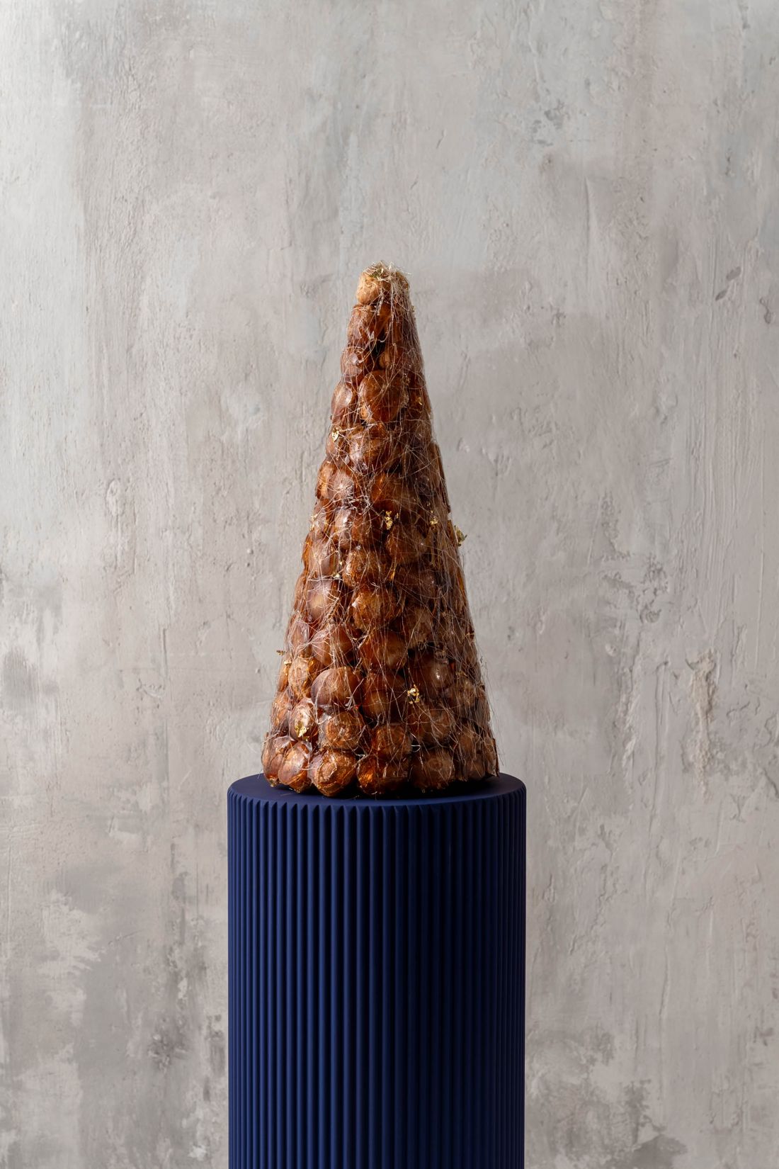 Croquembouche z karmelową nicią na granatowym postumencie