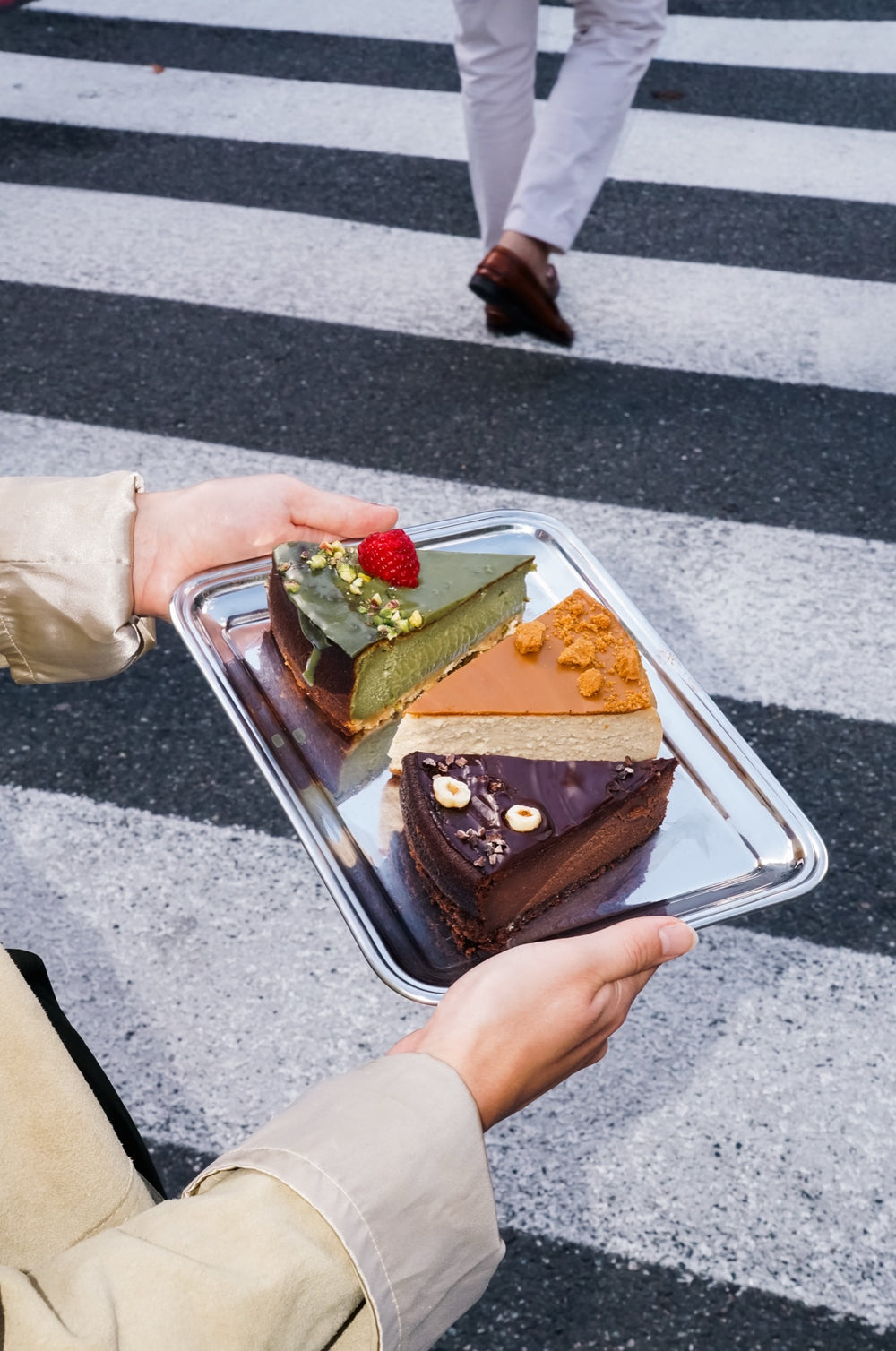 Taca z kawałkami serników Batida: matcha, lotus i czekoladowy, nad pasami na jezdni