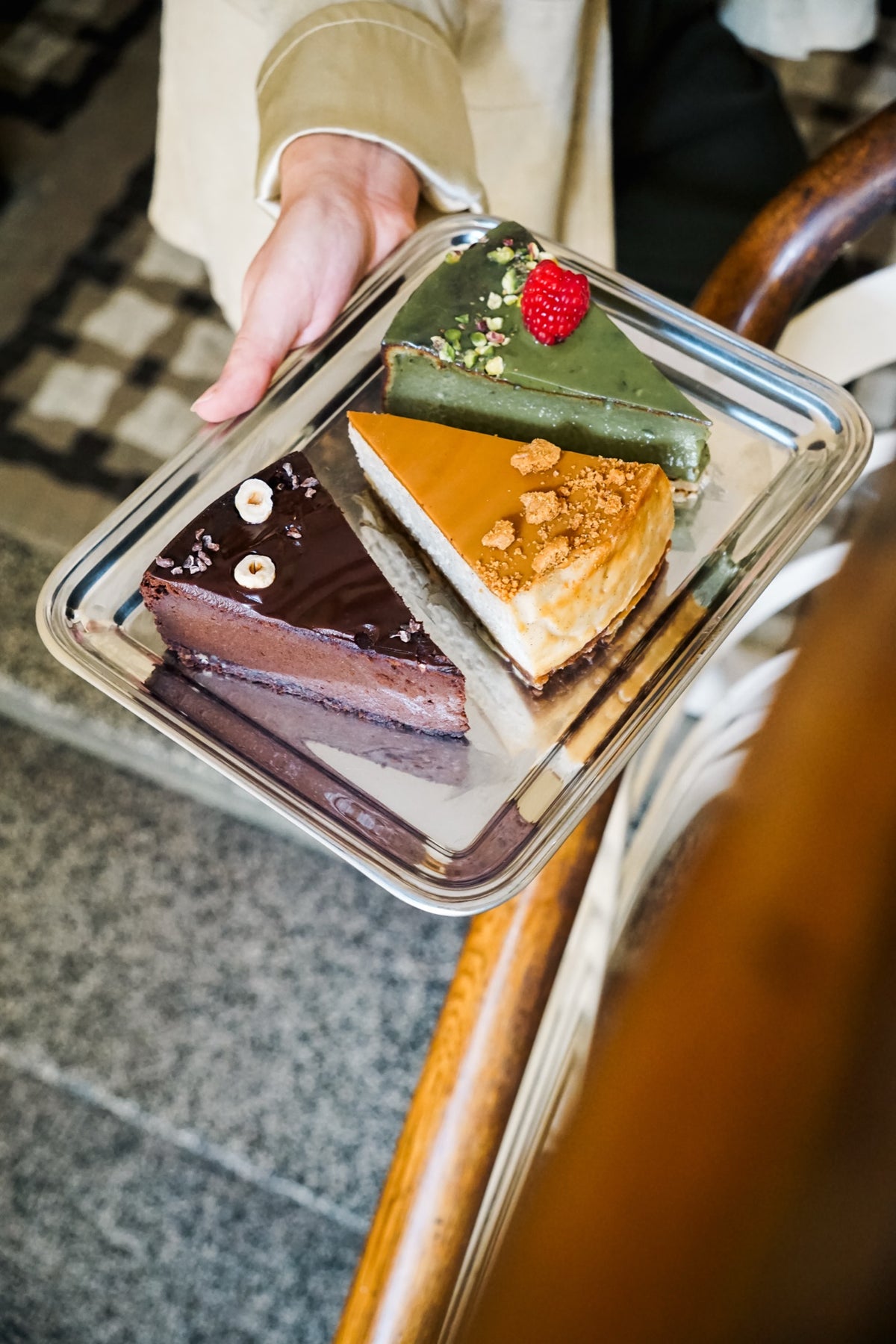 Serniki matcha, lotus i czekoladowy Batida na tacy przy kawiarnianym krześle