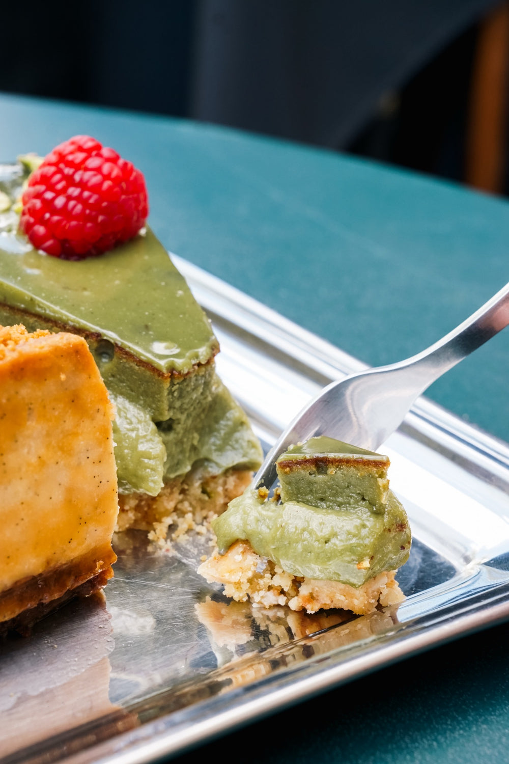 Sernik matcha Batida z maliną i pistacjami, kawałek na widelcu