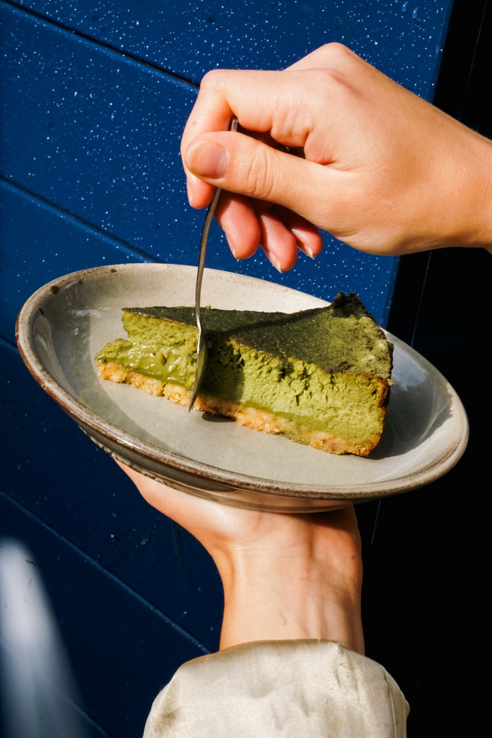 Sernik matcha Batida na talerzu na tle niebieskiej ściany