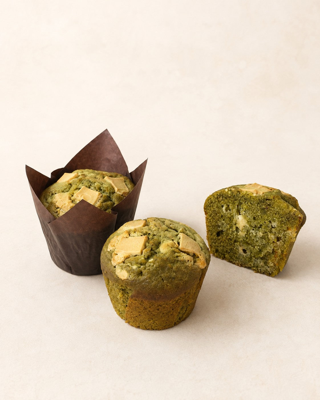 Muffin Matcha au chocolat blanc de Batida - deux muffins, avec et sans caissette, et une moitié montrant la coupe