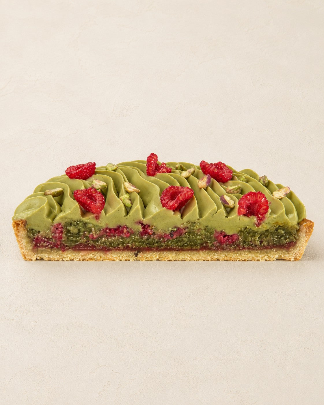 Tarta pistacjowa frangipane z malinami Batida - połówka tarty z boku, przekrój frangipane z malinami