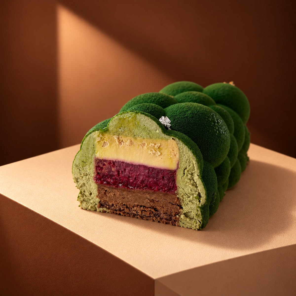 Przekrój Bûche de Noël - mus pistacjowy, insert malinowy i piernikowy biszkopt