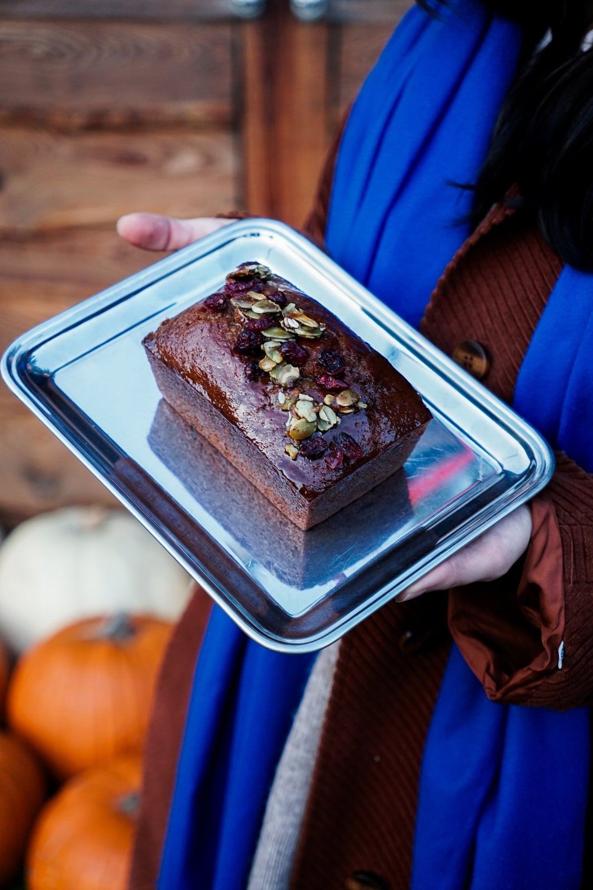 Chlebek dyniowy z żurawiną na tacy trzymanej w dłoniach