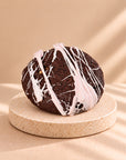 Chocolate crumble cookie with a white and pink icing spiderweb