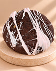 Chocolate crumble cookie with an icing spiderweb, close-up from above