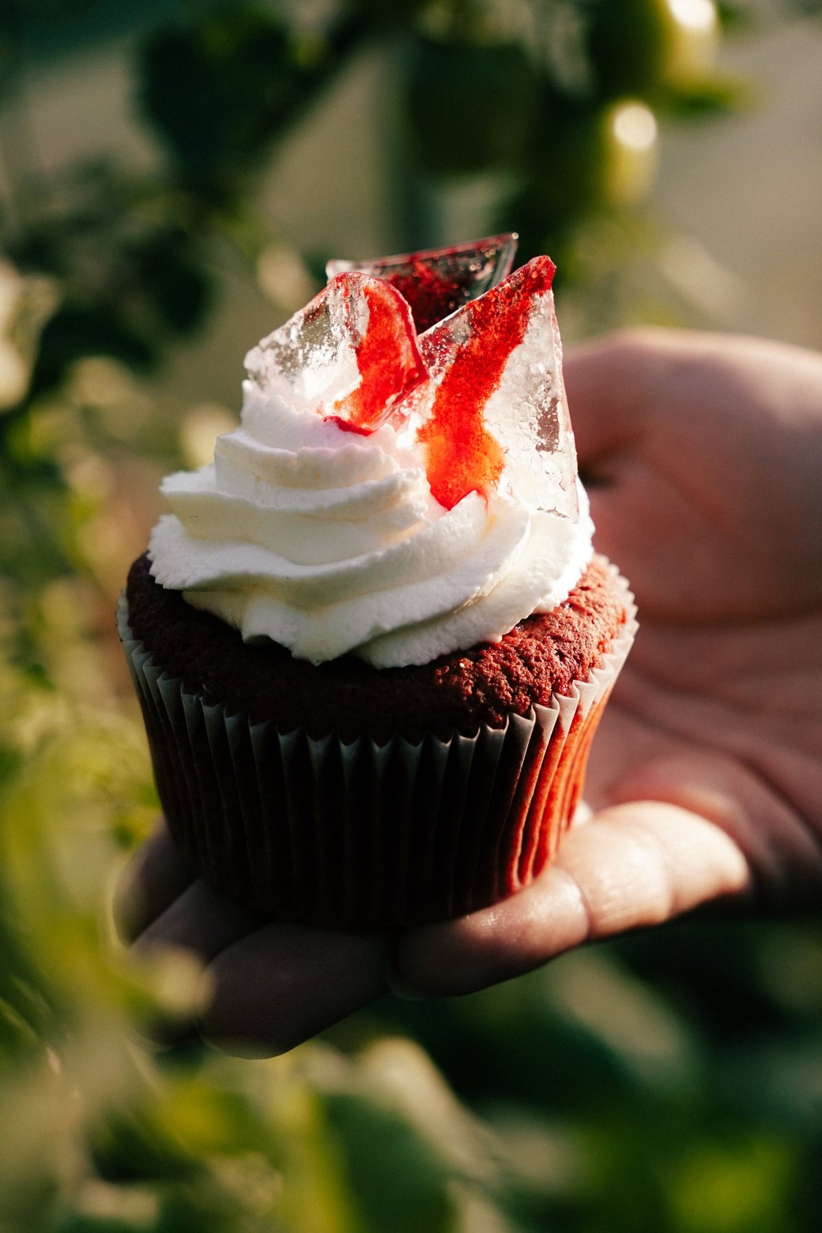 Muffin red velvet Halloween z czerwonym cukrowym szkłem wśród zieleni