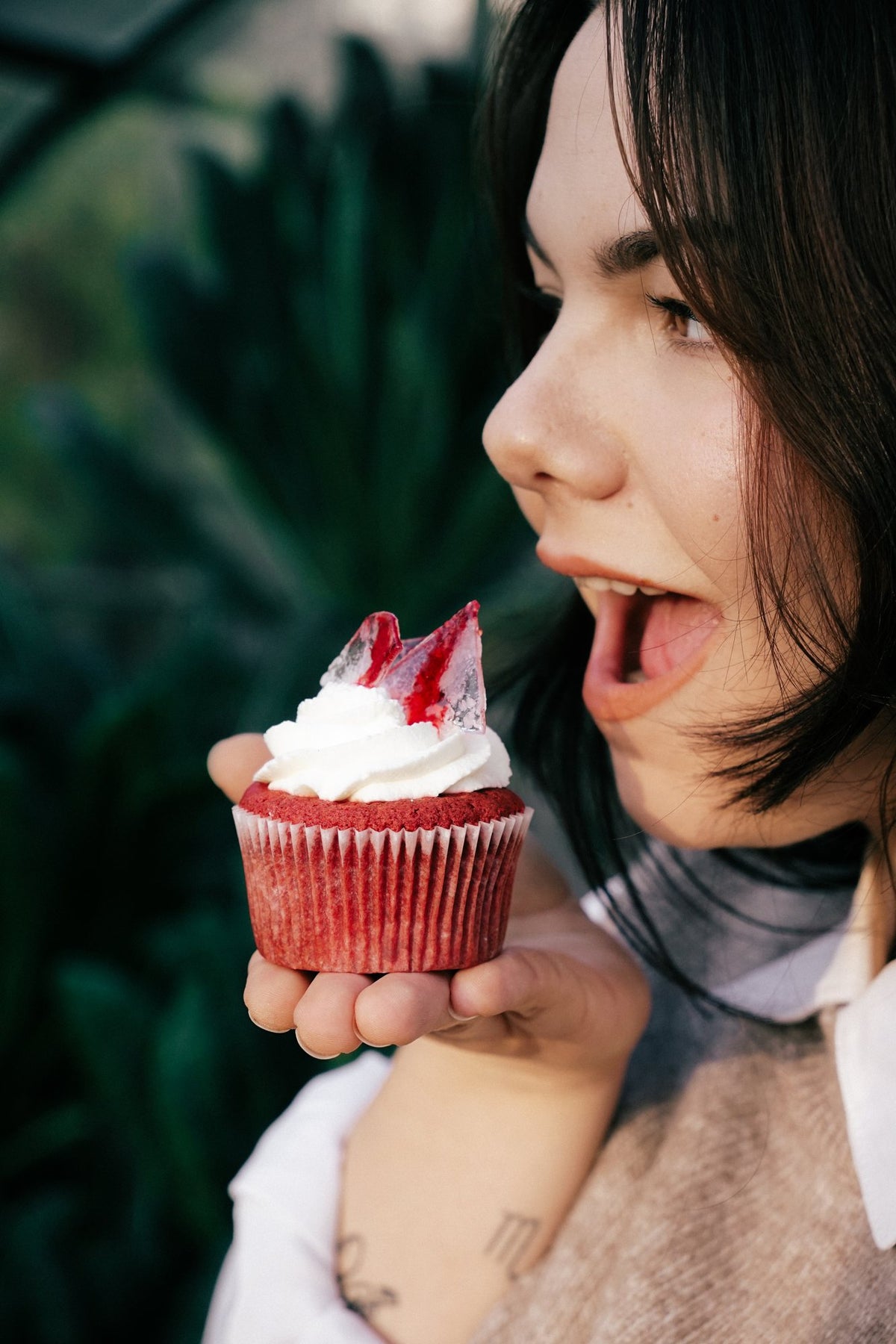 Dziewczyna gryzie muffina red velvet z halloweenową dekoracją