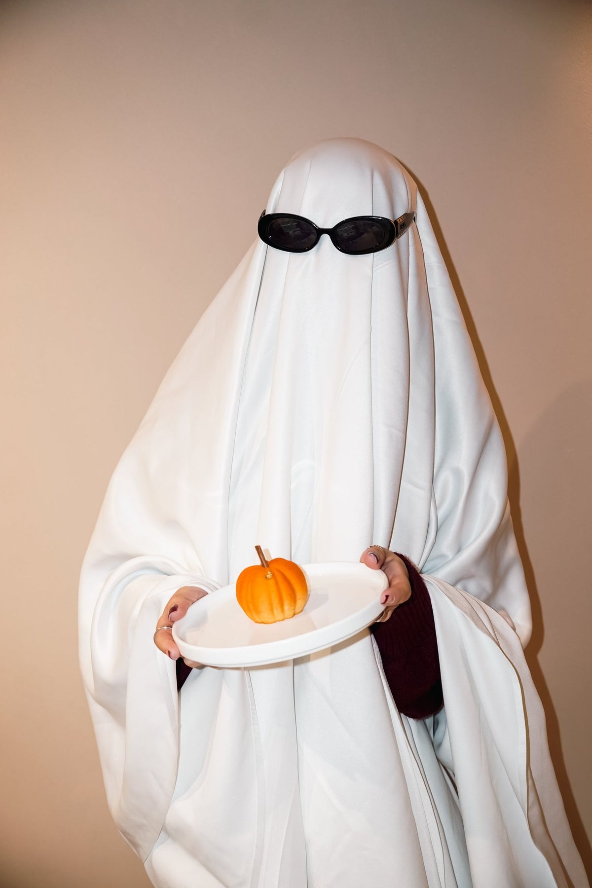 Duch trzyma talerzyk z pomarańczową monoporcją Pumpkin Latte w kształcie dyni
