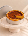Pumpkin cheesecake in a can with a slice cut out, on a marble cake stand