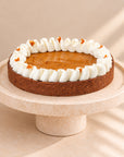 Pumpkin tart on a chocolate base with vanilla cream on a cake stand